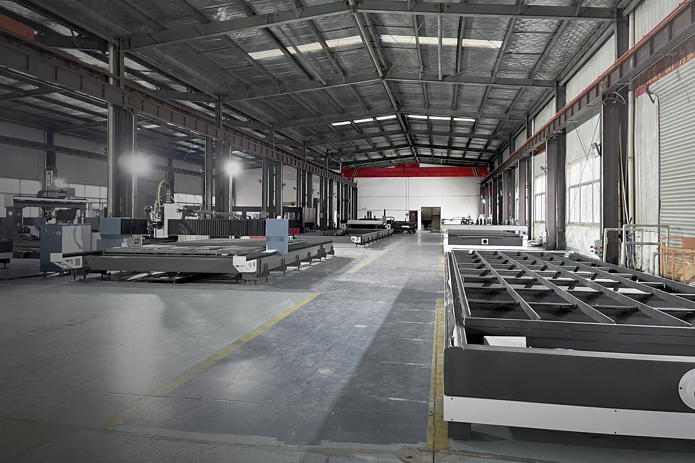 Interior of the TAIYI plant, with flat-bed laser cutting machines and a ground-rail cutting machine lined up along the shop floor